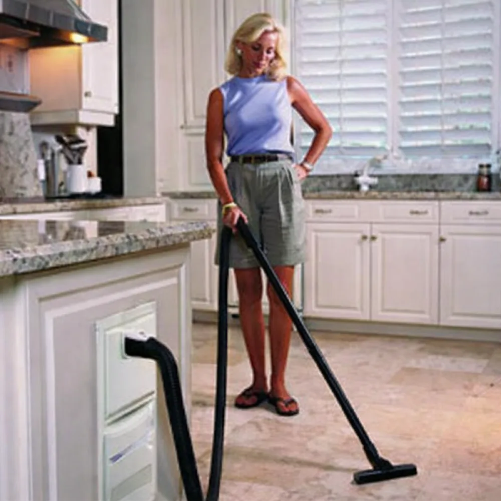 Homeowner vacuuming the kitchen with a built-in InterVac central vacuum